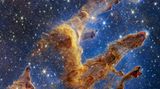 Schon Hubble lieferte ikonische Bilder der "Säulen der Schöpfung" im 6500 Lichtjahre entfernten Adlernebel. Der Infrarotdetektor des James-Webb-Teleskops zeigt die Sternenfabrik weitaus detaillierter als die Aufnahmen im sichtbaren Licht. Gut zu erkennen sind die hellrot leuchtenden neugeborenen Sterne an den Spitzen der Säulen. Dort ist der Staub am dichtesten, sodass er unter seiner eigenen Gravitation zusammenfällt, sich aufheizt und schließlich neue Sterne entstehen. Hinter den Säulen erscheinen unzählige weitere Sterne und Galaxien