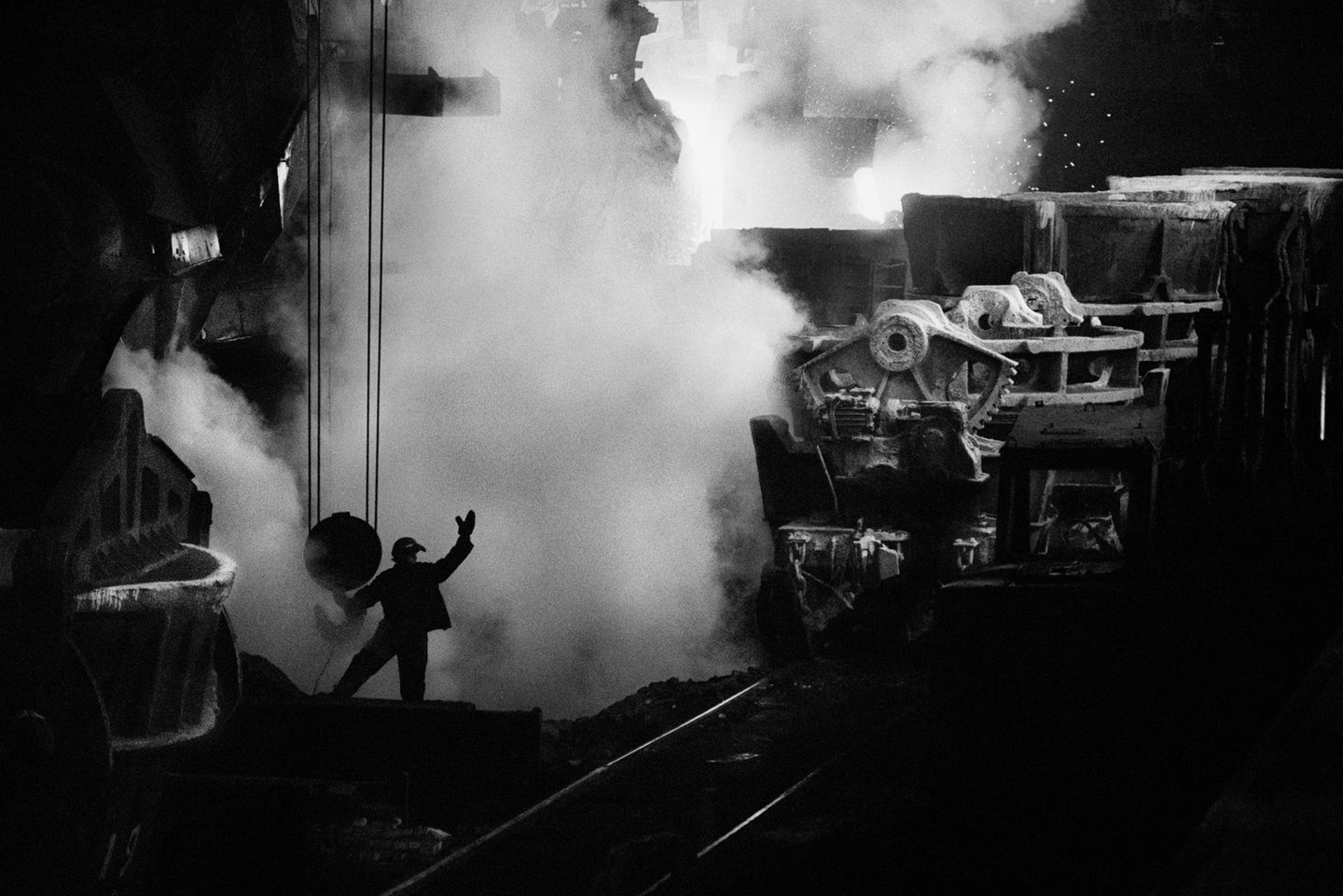 Ein Foto, das an avantgardistische Aufnahmen erinnert: Große Maschinen, kleiner Mensch. Ein Arbeiter in einem Stahlwerk