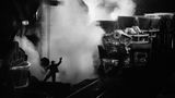 Ein Foto, das an avantgardistische Aufnahmen erinnert: Große Maschinen, kleiner Mensch. Ein Arbeiter in einem Stahlwerk
