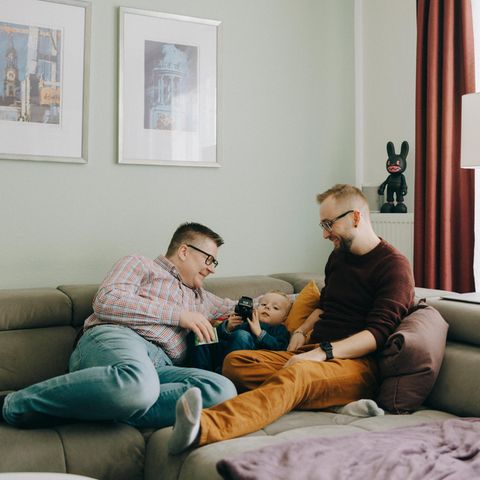 Chris und Martin liegen mit ihrem Sohn auf der Couch