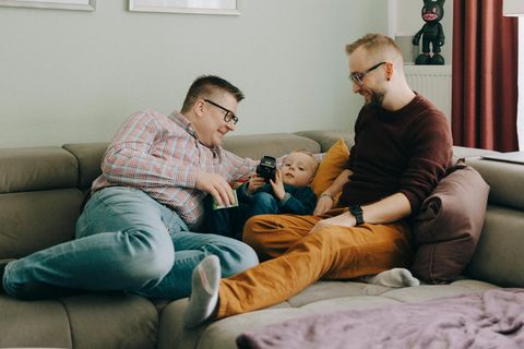 Chris und Martin liegen mit ihrem Sohn auf der Couch