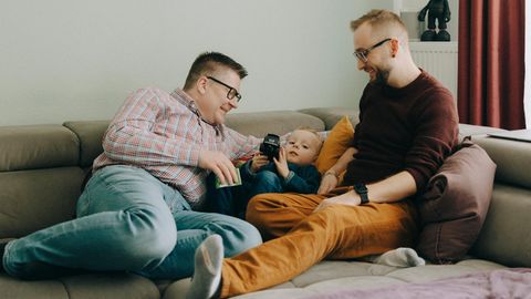 Chris und Martin liegen mit ihrem Sohn auf der Couch