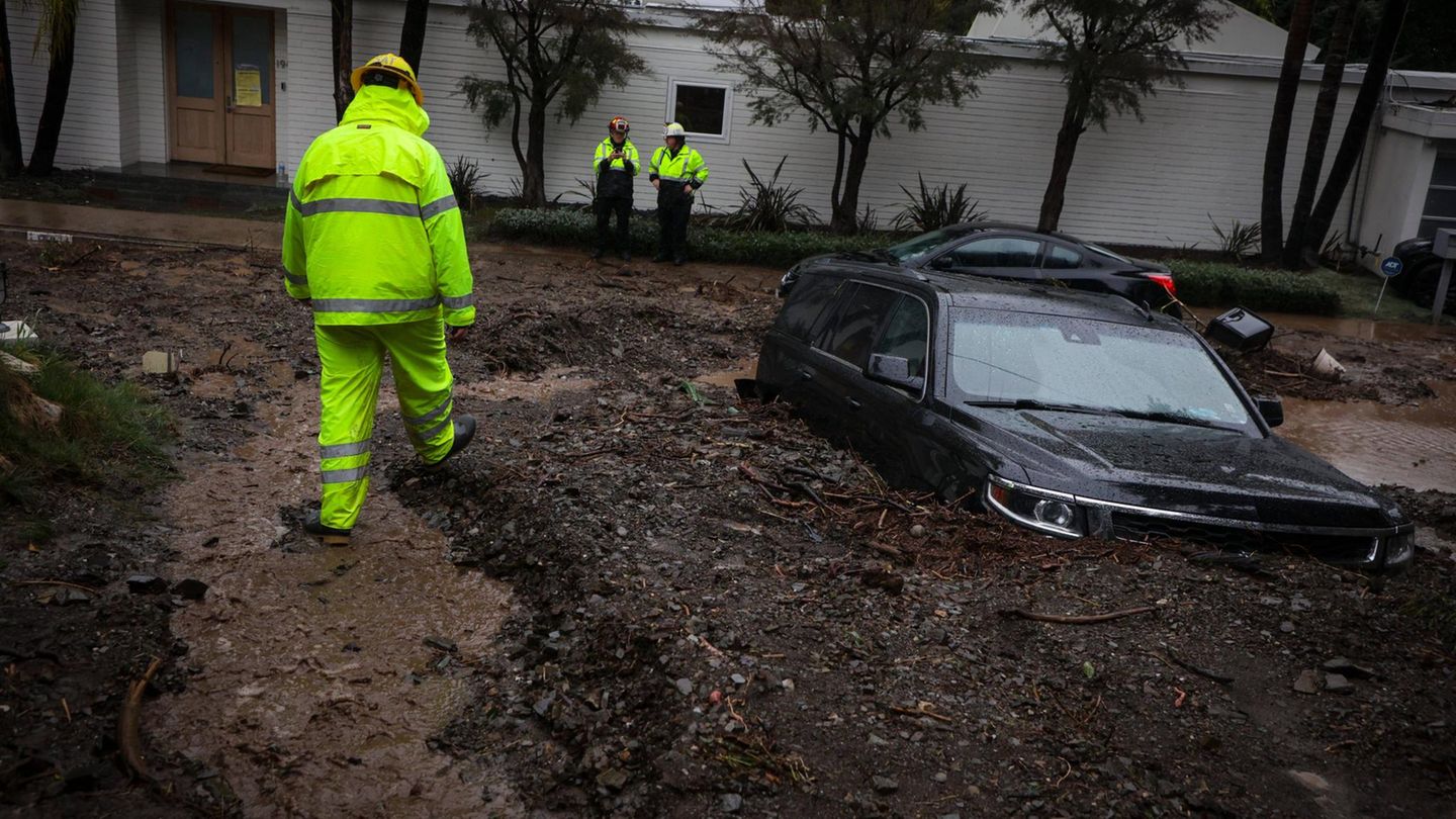 Feuerwehrleute begutachten ein im Schlamm feststeckendes Auto in kalifornien