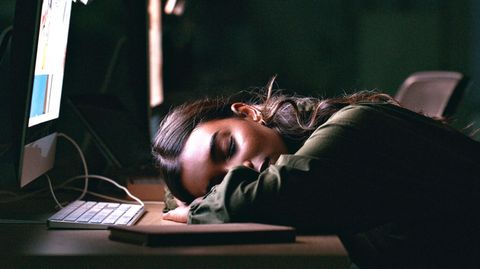 Eine Frau sitzt erschöpft vor dem Laptop.