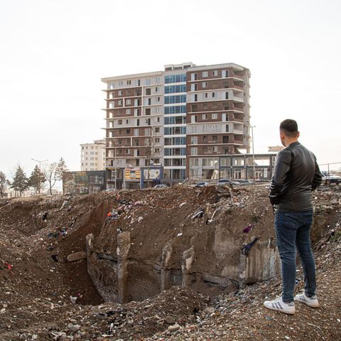 Ein junger Mann steht an einem Erdloch in einer Stadt in der Türkei die durch das Erdbeben zerstört wurde