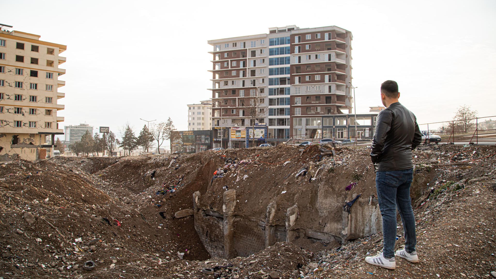 Ein junger Mann steht an einem Erdloch in einer Stadt in der Türkei die durch das Erdbeben zerstört wurde