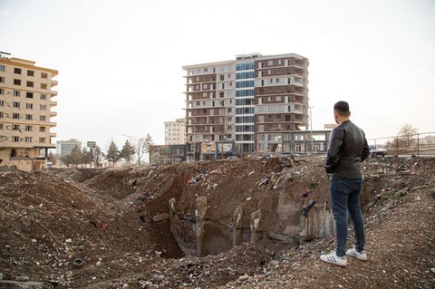 Ein junger Mann steht an einem Erdloch in einer Stadt in der Türkei die durch das Erdbeben zerstört wurde