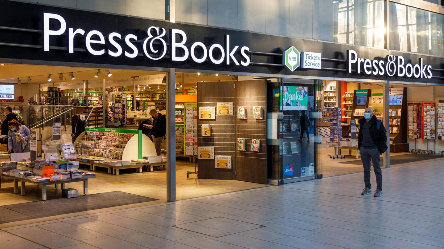 Vor einer Bahnhofsbuchhandlung laufen Menschen entlang