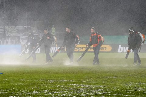 DFB-Pokal: Mit Laubbläsern versuchen Helfer, Wasser vom Rasen in Saarbrücken zu bekommen
