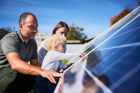 Wechselrichter: Vater, Mutter und Kind begutachten Solarmodule auf Hausdach