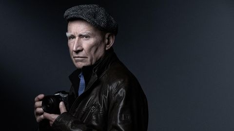Portrait des Fotografen Sebastiao Salgado mit Kamera in der Hand