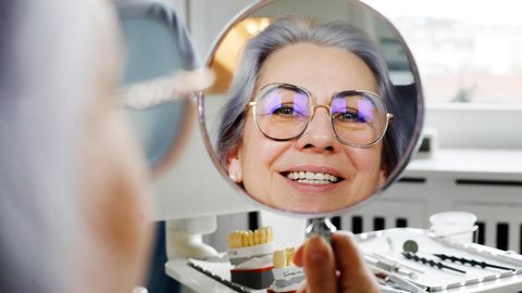 Zahnmedizin: Patientin Liliia Schairer lächelt in den Spiegel