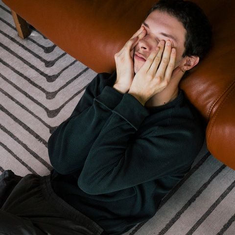 Ein junger Mann lehnt verzweifelt an einer Leder Couch