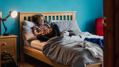 Symbolbild zu Hoss und Hopf: Ein Junge liegt auf seinem Bett und hört etwas mit Kopfhörern