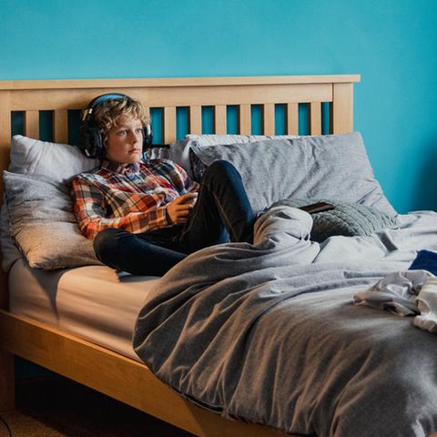 Symbolbild zu Hoss und Hopf: Ein Junge liegt auf seinem Bett und hört etwas mit Kopfhörern