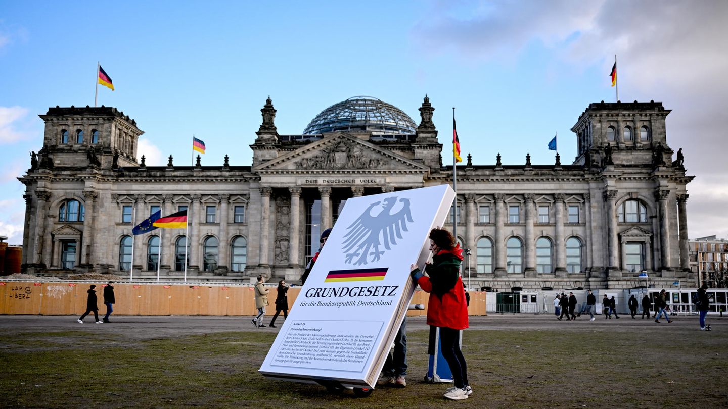 Aktivisten stellen einen Aufsteller mit dem Aufdruck "Grundgesetz" vor dem Reichstag auf