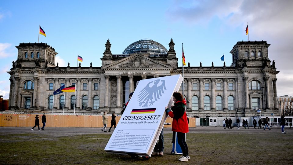Aktivisten stellen einen Aufsteller mit dem Aufdruck "Grundgesetz" vor dem Reichstag auf