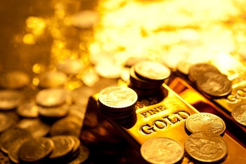Ein Goldbarren und mehrere Goldmünzen