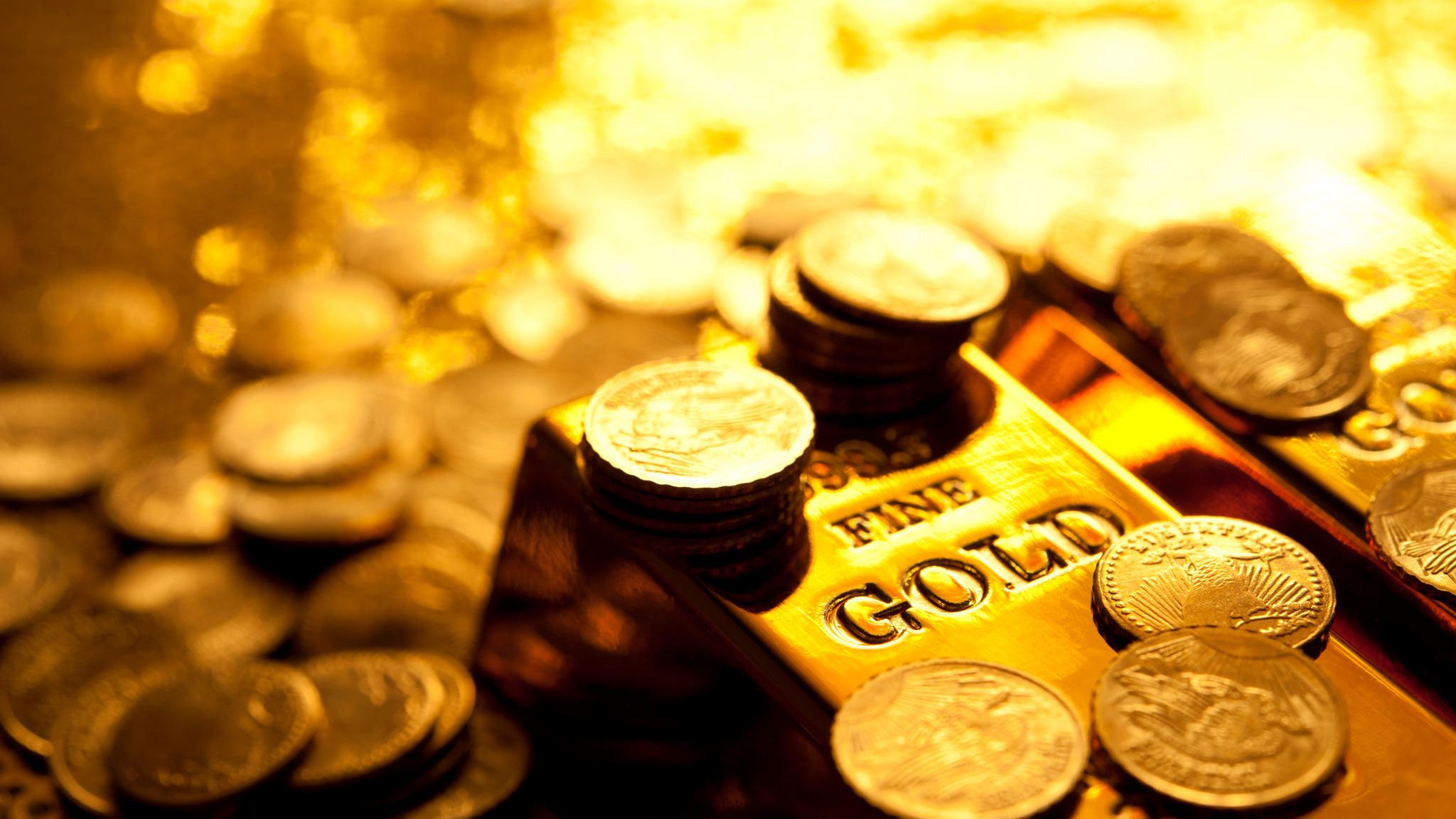 Ein Goldbarren und mehrere Goldmünzen Ein Goldbarren und mehrere Goldmünzen