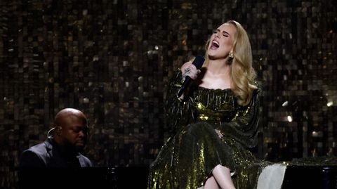 Adele sitzt bei einem Konzert auf einem Flügel.