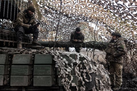 Verteidigung: Ukrainische Soldaten unterhalten sich, während einer sich auf das Geschütz eines Panzers stützt