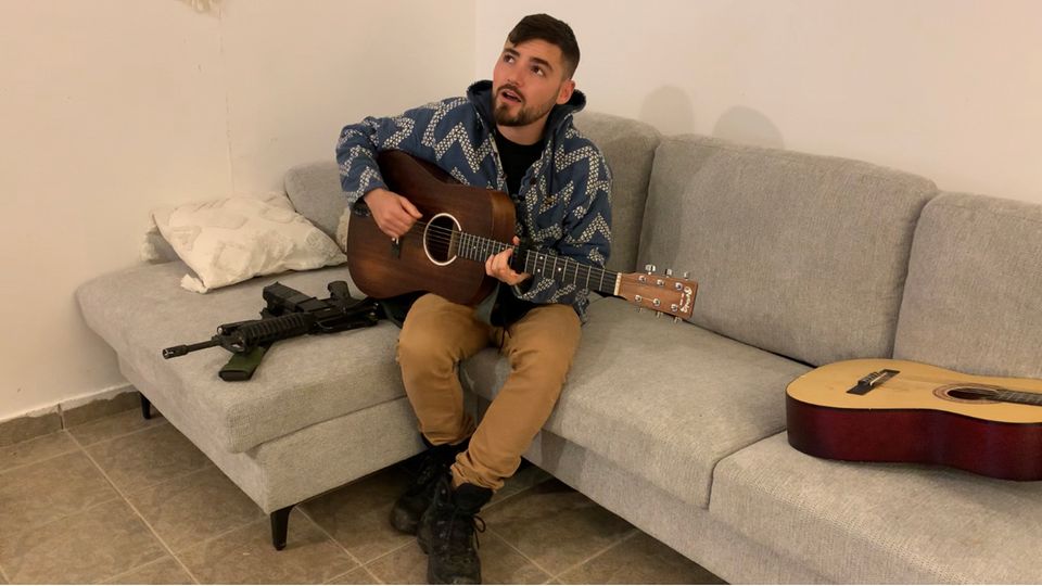 Omri Goren zu Hause in Jerusalem. Der 28-Jährige ist Sänger und seit dem 7. Oktober als Reservist in der Armee eingesetzt. Maschinengewehr und Gitarre sind seine ständigen Begleiter