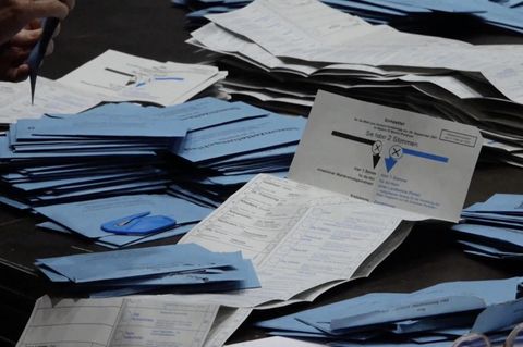 Wahlumschläge und ein geöffneter Wahlzettel liegen auf einem Tisch.