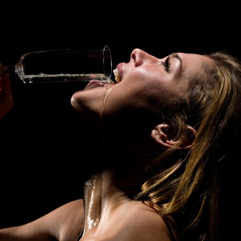 Eine Frau schüttet sich ein Glas Champagner in den Mund