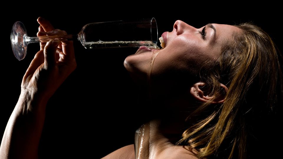 Eine Frau schüttet sich ein Glas Champagner in den Mund