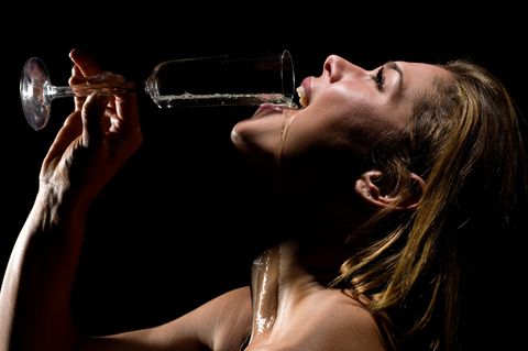 Eine Frau schüttet sich ein Glas Champagner in den Mund