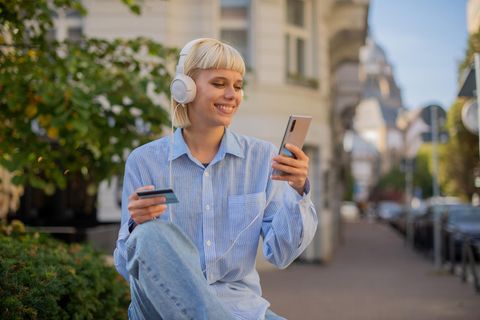 Junge Frau mit Amex Kreditkarte beim Online-Shopping.