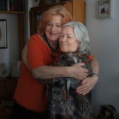Ilse und Beate umarmen sich in ihrem Wohnzimmer