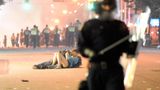 Ein Paar liegt auf dem Boden und küsst sich. Umliegend laufen Polizisten.