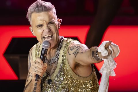 Robbie Williams  auf der Bühne in einem goldenen Outfit.