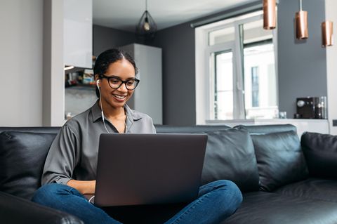 Junge Frau sitzt mit Einsteiger-Laptop auf dem Sofa.