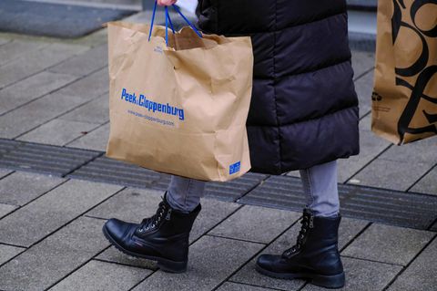 Kundin trägt Einkaufstüte von Peek & Cloppenburg durch Ladenzeile.