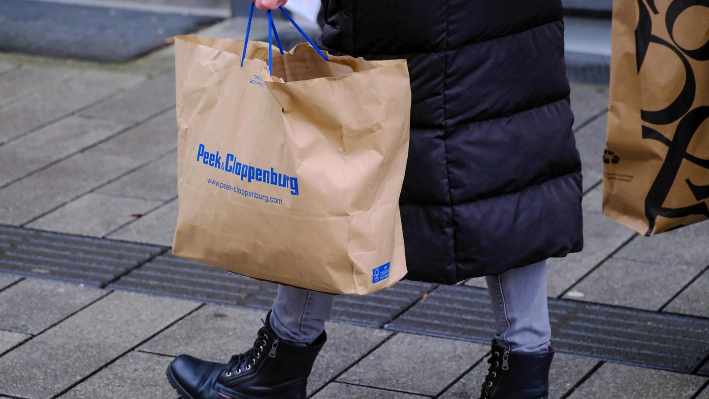 Kundin trägt Einkaufstüte von Peek & Cloppenburg durch Ladenzeile.