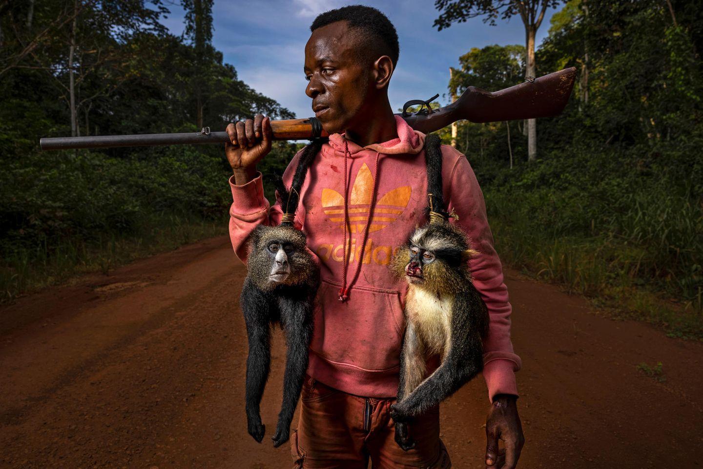 Kongo-Jäger Jonas Manguba mit zwei erschossenen Affen und einem Gewehr