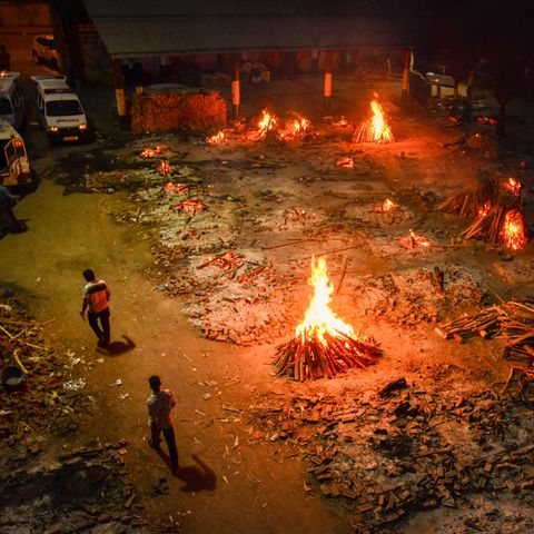 Zwei Männer gehen vorbei an Holzfeuern auf dem Gelände eines Krematoriums in Indien