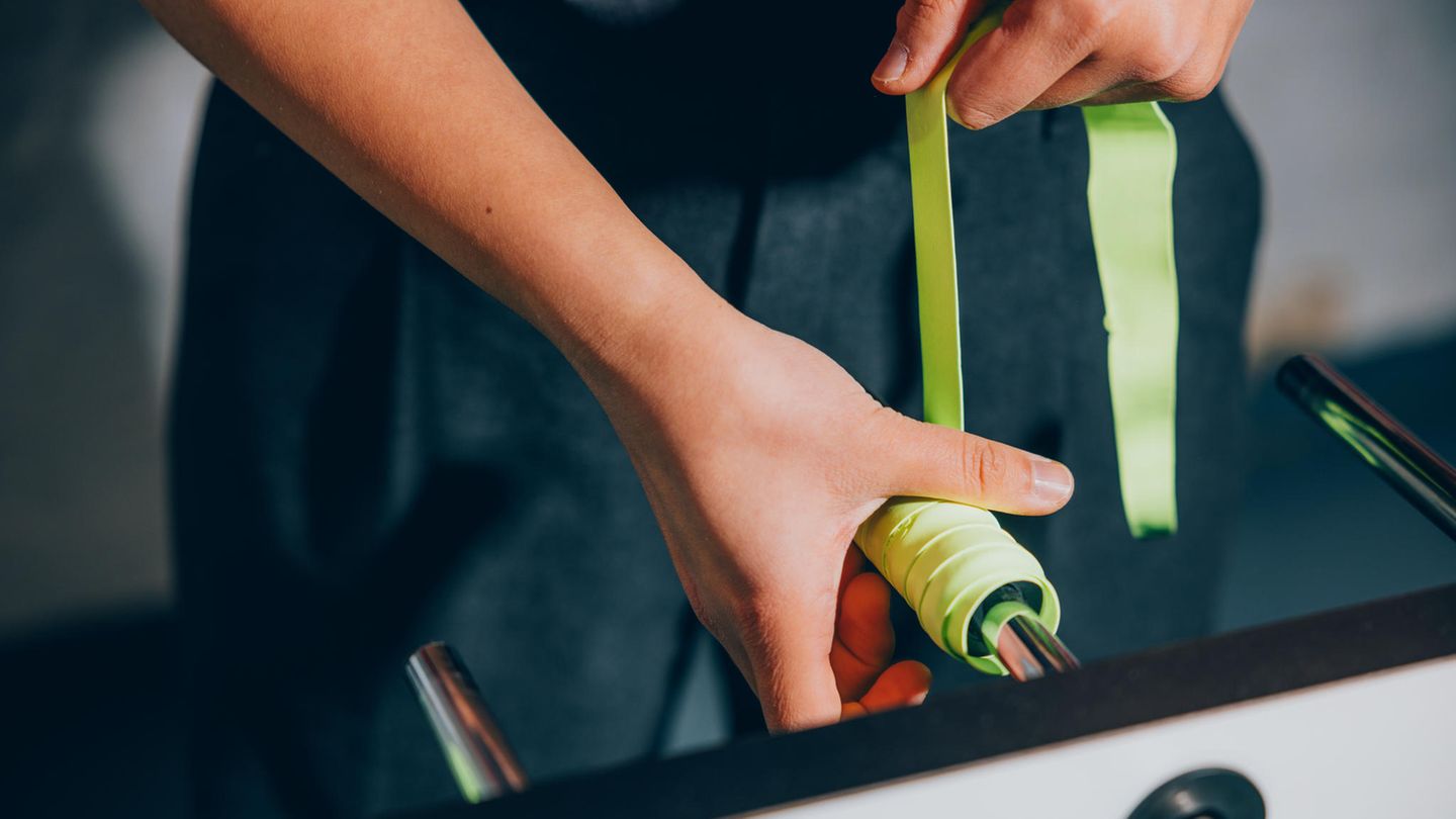 Hände die ein gelbes Grippband um den Griff wickeln