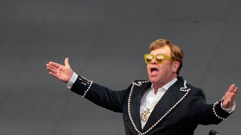  Elton John breitet bei einem Konzert auf der Bühne seine Arme aus