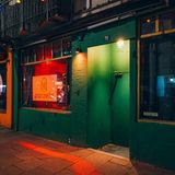 Es ist Nacht. Bunte Lichter leuchten aus den Scheiben der Bar