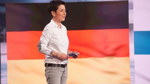 Dunja Hayali im TV vor einer Deutschland-Flagge