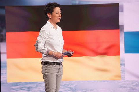 Dunja Hayali im TV vor einer Deutschland-Flagge