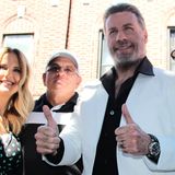 John Travolta in seinem berühmten weißen Anzug, den er in "Saturday Night Fever" getragen hat. Links ist seine Frau Kelly Preston, mit der er 1989 zusammenkam und die er 1991 geheiratet hat. Das Paar bekam zwei gemeinsame Söhne und eine Tochter. 