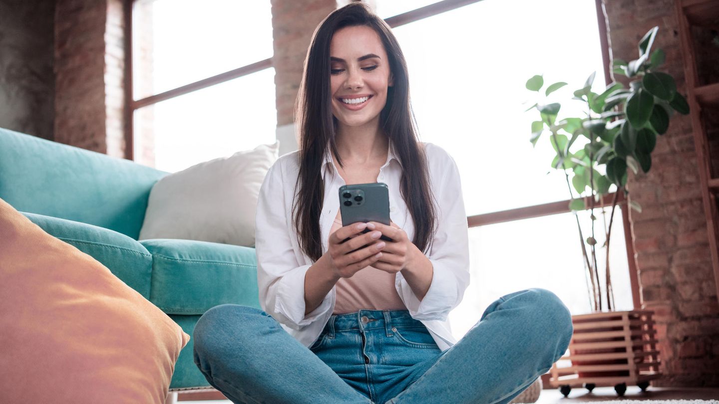 iPhone 14 Pro vs. iPhone 15 Pro: Ein Frau schaut freudig auf ihr iPhone 14 Pro