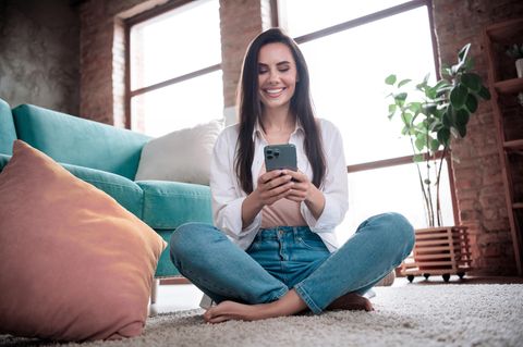 iPhone 14 Pro vs. iPhone 15 Pro: Ein Frau schaut freudig auf ihr iPhone 14 Pro