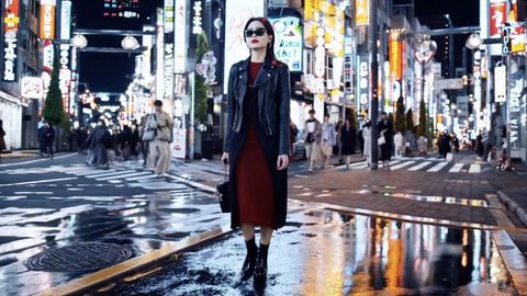 Eine Frau in einem roten Kleid läuft eine Straße in Tokyo entlang.
