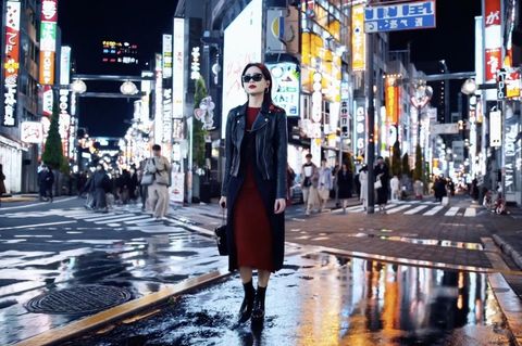 Eine Frau in einem roten Kleid läuft eine Straße in Tokyo entlang.