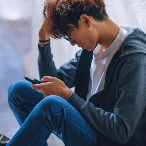 Symbolfoto zum Thema Dating: Ein junger Mann schaut frustriert auf sein Handy